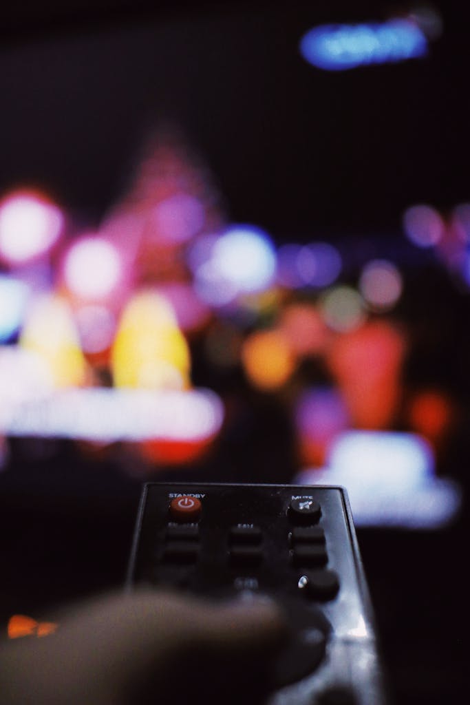 Soft focus of person with TV remote switching channels while watching movie in living room at home during free time